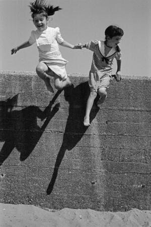photo d'enfants qui sautent d'un muret dans le sable
